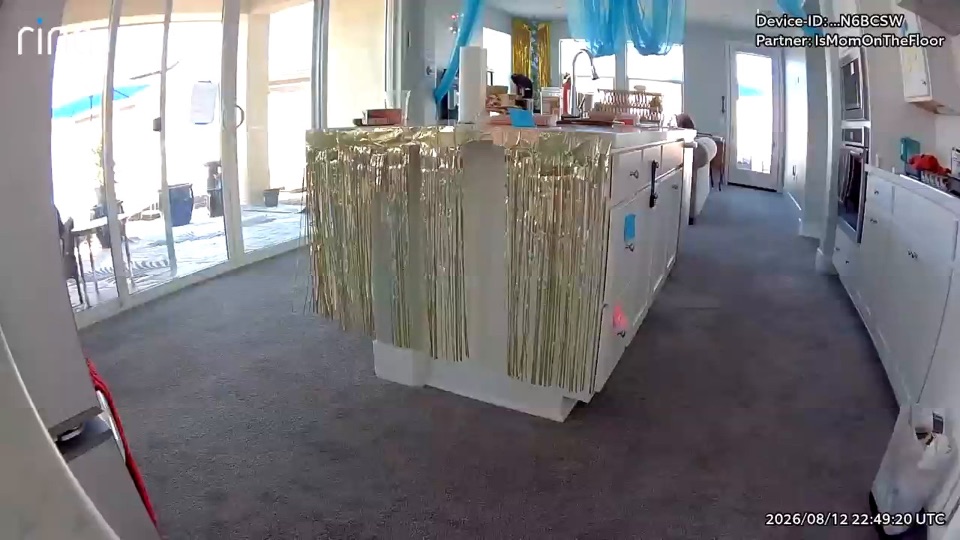 A kitchen with a metallic tinsel skirt around the island and blue streamers overhead. No one is in the room.